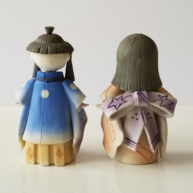 後ろ向きに置かれた男の子と女の子の人形ふたつ。
