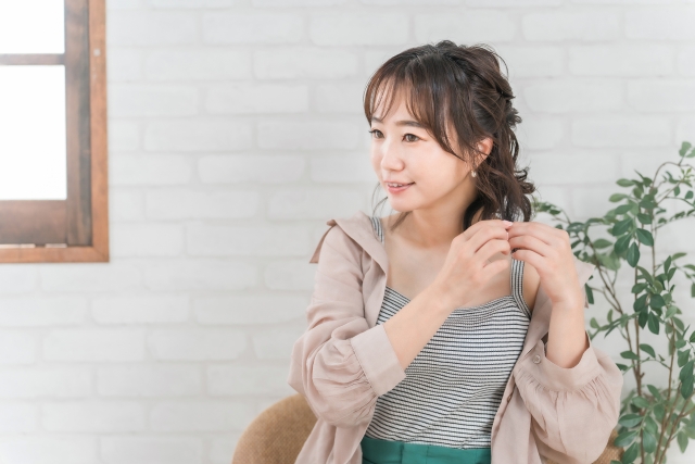 くるくるした毛先をいじって髪型を整えている若い女性