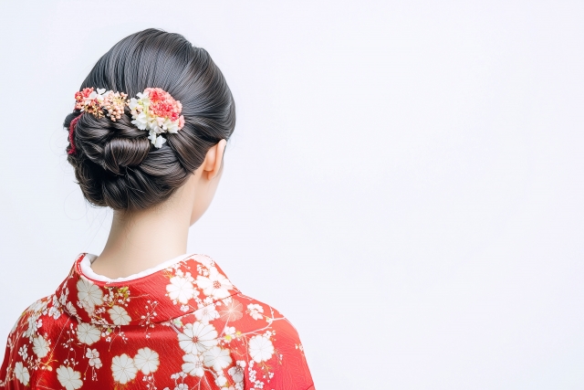 赤い着物を着た女性の後ろ姿。黒く艶やかなまとめ髪が美しい。