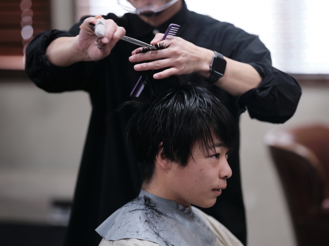 理容師に髪を切ってもらっている少年