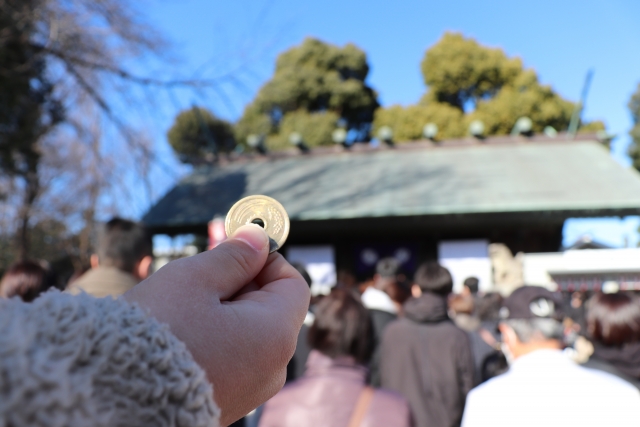 神社で、賽銭用の五円玉をもつ手
