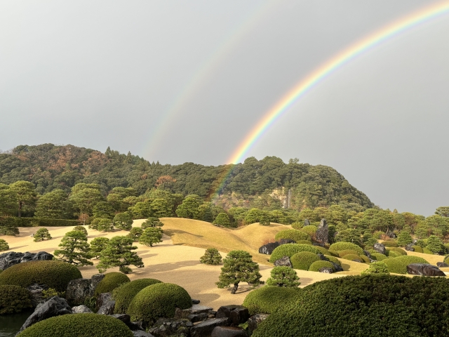 管理されてすっきりとした姿を見せる日本庭園。空には虹が見える。