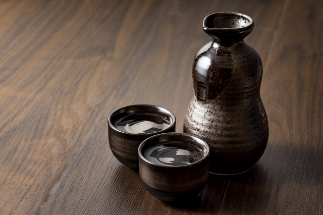 木のテーブルにおかれた茶色の徳利と猪口
